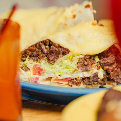 Burrito filled with beef, lettuce, tomatoes, melted cheese.