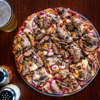 Pizza topped with sausage, fresh mushrooms, and red onions, served with a glass of beer.
