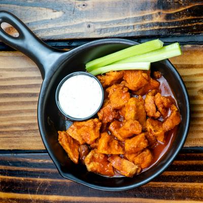 Chicken Bites served in a skillet with celery sticks and dipping sauce.