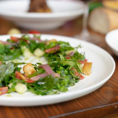 Salad with arugula, pickled onions, tomatoes, and croutons, close-up.