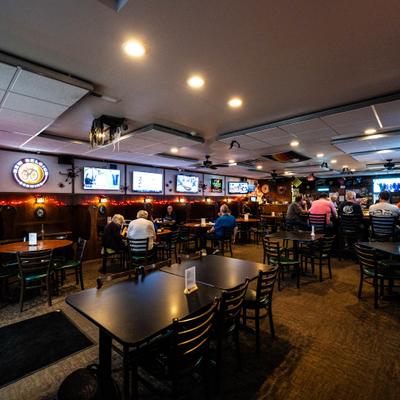 Interior with tables and chairs, bar and  multiple TV screens.