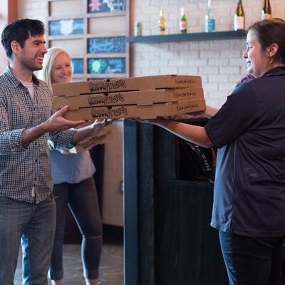 Guests picking up three pizza boxes