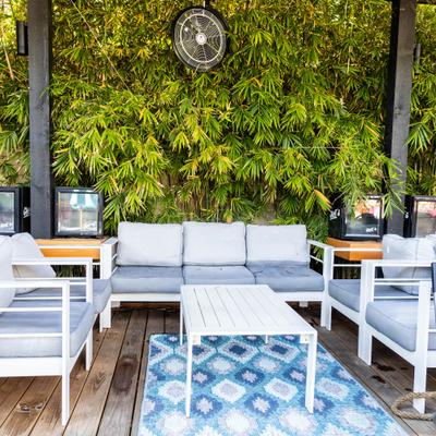 Outdoor lounge area featuring white modern furniture and a geometric blue patterned rug.