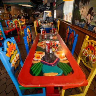 Interior featuring hand-painted wooden tables and matching multi-colored chairs.