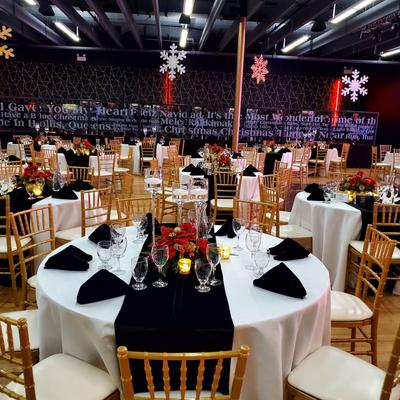 Dining area with round tables featuring black-and-white table runners and black napkins.
