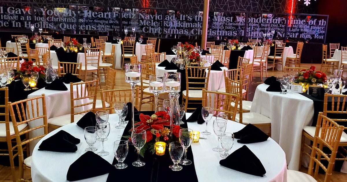 Dining setup featuring round tables with black table runners and floral centerpieces