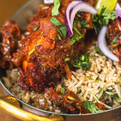 Spiced chicken curry served over seasoned rice with onions and herbs.