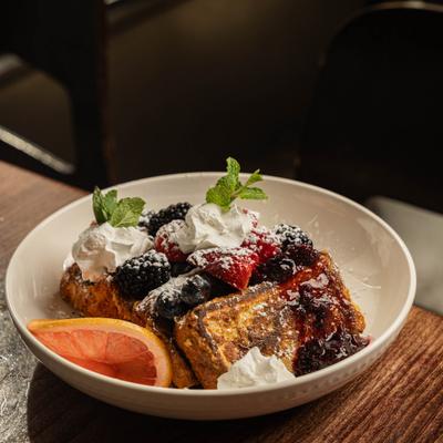 French toast topped with berries, whipped cream and powdered sugar.