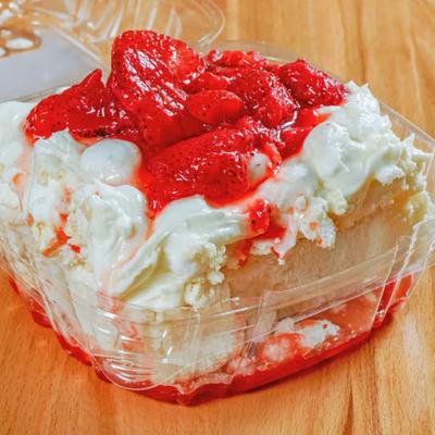 Strawberries on A Cloud dessert served in clear plastic container, on a wooden table.