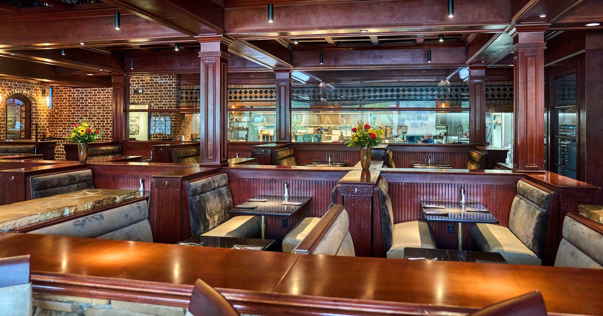 Upscale restaurant interior -  wooden booths, upholstered seats and visible kitchen