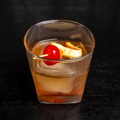 Old Fashioned, garnished with orange peel and a cocktial cherry.