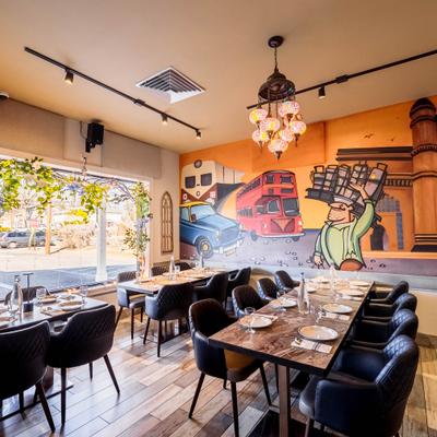 Dining tables with plates and glassware, the room decorated with a vibrant mural.