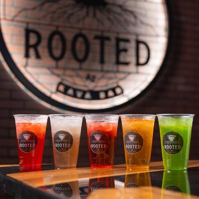 Assorted colorful drinks on a bar counter with the logo in the background.