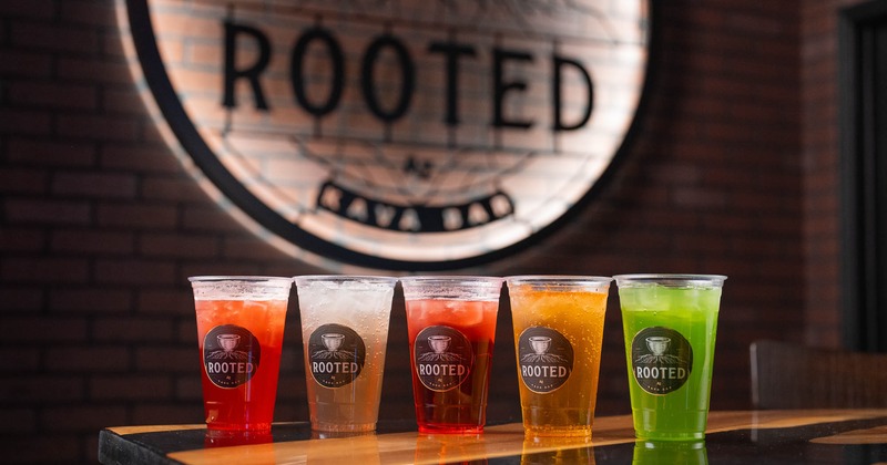 Assorted colorful drinks on a bar counter with the logo in the background