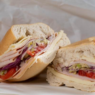 Turkey sandwich with cheese, lettuce, tomato, red onion, and mayo.