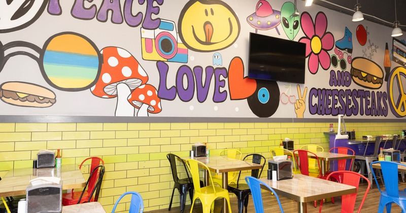 Colorful restaurant mural with cartoon illustrations; bright yellow tile wall and colorful seating.