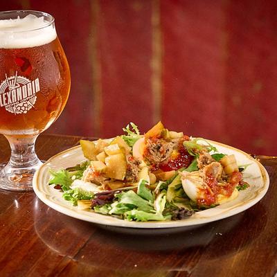 Plated savory egg appetizers served alongside a cold glass of amber beer.