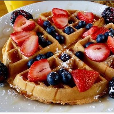 Waffles topped sprinkled with powdered sugar, topped with strawberries and blueberries.