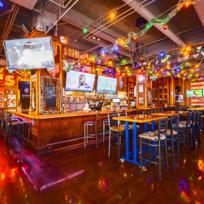 Bar area's interior with counter, stools and multiple TV screens.