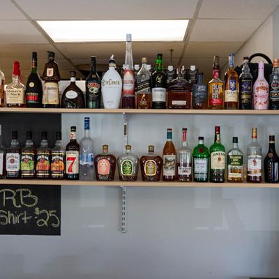 Interior, bottles of hard liquor lined up on shelves.