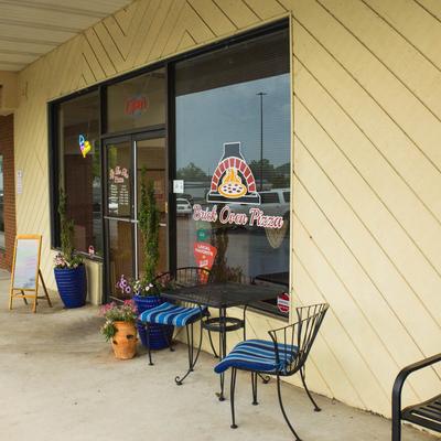 Storefront with outdoor seating and potted plants.