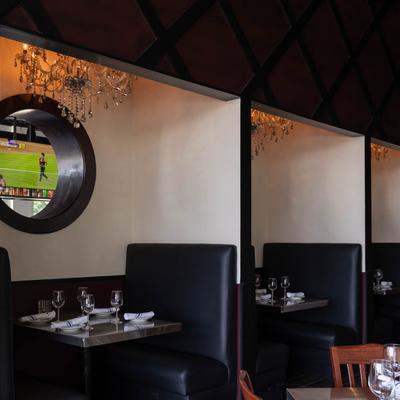 Interior, partitioned restaurant booths with tableware on tables.
