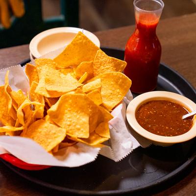 Tortilla chips with spicy salsa and a bowl of dark red dip.