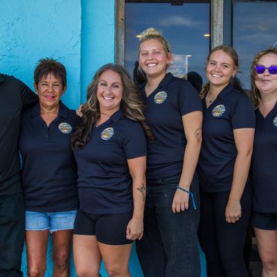 Staff members posing in front of the restaurant's entrance.