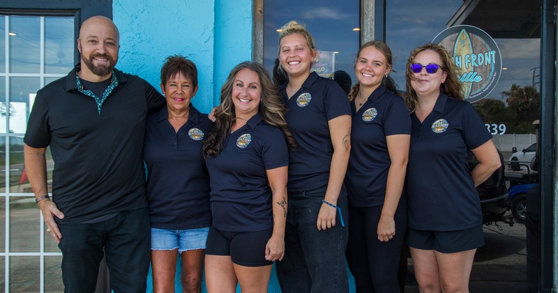 Staff members posing in front of the restaurant's entrance