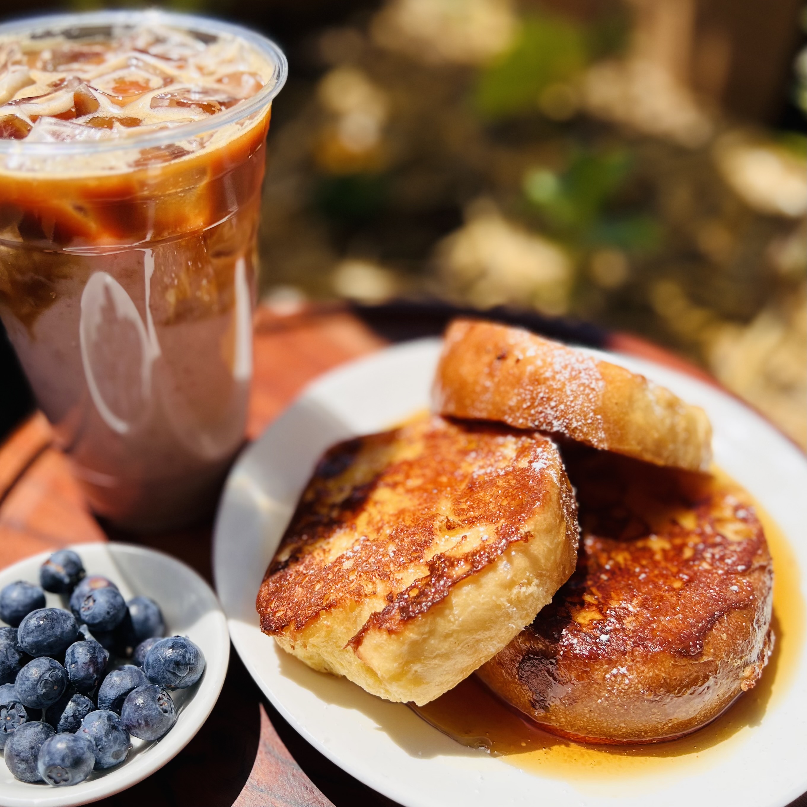 French toast with maple syrup, blueberries, and a cup of iced coffee