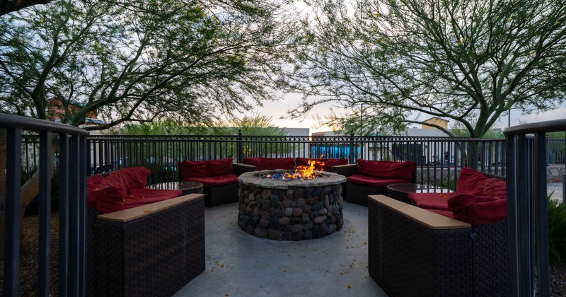 Exterior, lounge area, outdoor sofas around the stone fire pit, encircled with metal railing