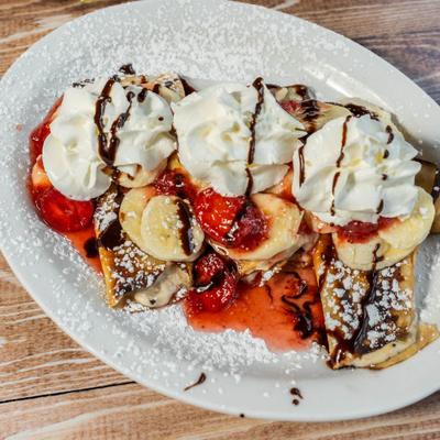 Crepes with bananas, strawberries, and whipped cream.