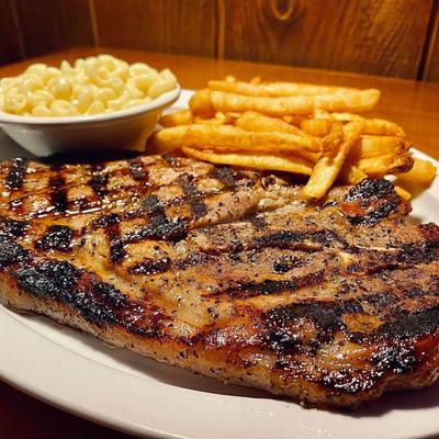 Grilled steak served with mac and cheese and fries.