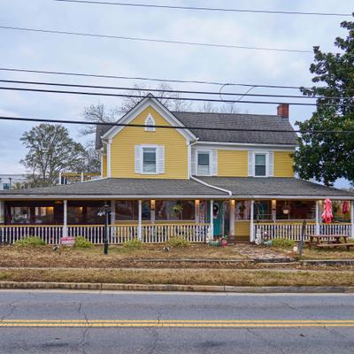 Front view of a yellow two-story building with a long covered porch.