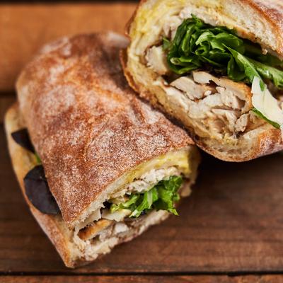 Sandwich with sliced chicken and  fresh greens, close-up.