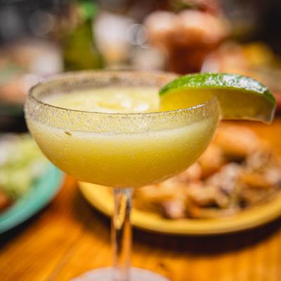 Close up of Margarita with assorted dishes in the background.