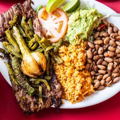 Grilled steak with roasted onions and peppers, beans, rice, guacamole.