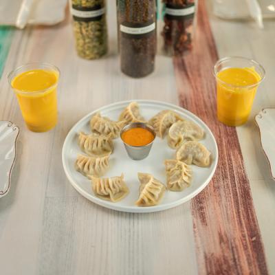 Chicken dumplings served with dipping sauce and two cups of mango lassi.