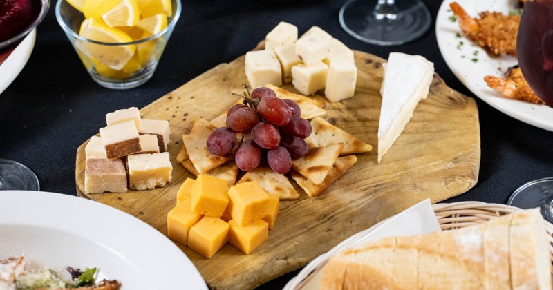 A cheese board surrounded by various dishes
