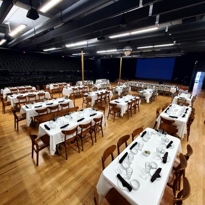 Banquet hall set up with rows of long tables covered in white tablecloths.