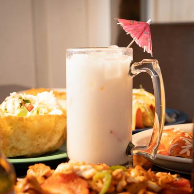A large margarita and various meals around it.