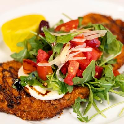 Pollo Milanese with arugula, diced tomatoes, grated cheese and balsamic dressing..
