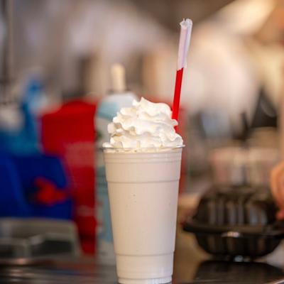 Milkshake topped with whipped cream and a red straw.