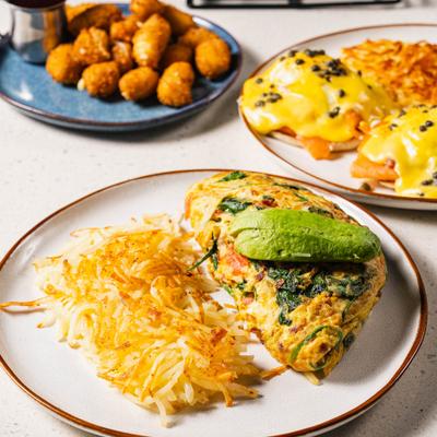 Bacon and vegetable omelet with avocado and hash browns.