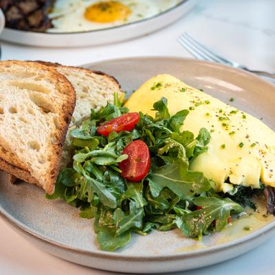 Mushroom French Omelet served with arugula salad and toasted bread slices.