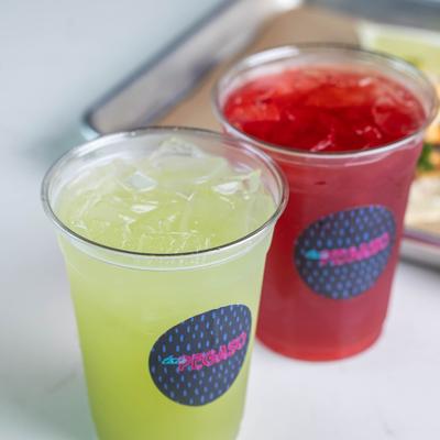 Green and red iced drinks beside a metal tray.