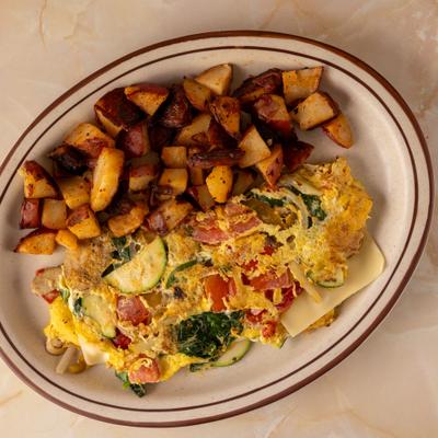 Vegetable omelet served with diced roasted red potatoes on a plate.