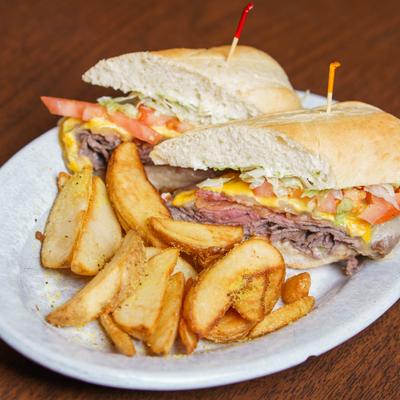 Hot Roast Beef sandwich with cheese, lettuce, tomato and a side of potato wedges.