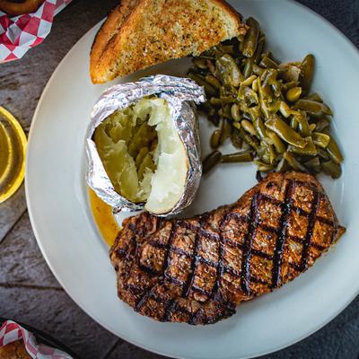 Grilled rib eye steak served with baked potato, green beans and toast bread.