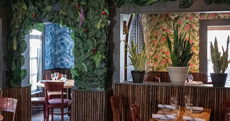Interior with tables and chairs, walls decorated with jungle leaves